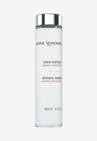 Heldere glazen fles met een kleurloze vloeistof. Zilveren dop. Witte en bruine etiketten met de teksten "Lotion Végétale" en "Botanical Toner." 200 ml.