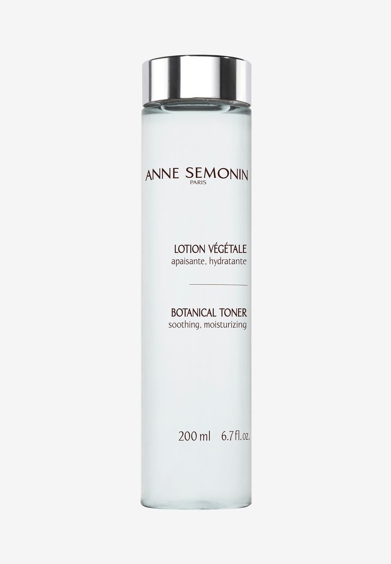 Heldere glazen fles met een kleurloze vloeistof. Zilveren dop. Witte en bruine etiketten met de teksten "Lotion Végétale" en "Botanical Toner." 200 ml.