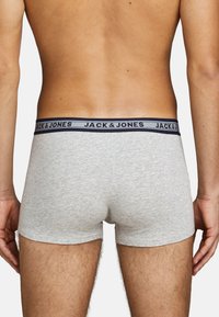 Grijze katoenen boxershorts met een marineblauwe tailleband met het "JACK & JONES" logo, weergegeven vanuit de achterkant. Soepel, aansluitend ontwerp.