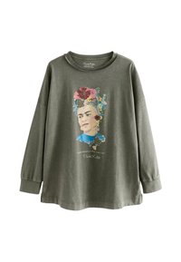Olive zelena majica z dolgimi rokavi s cvetličnim portretom in citatom Frida Kahlo. Mehka tkanina z sproščenim krojem in okroglim izrezom.