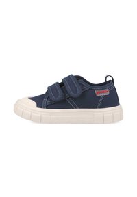 Zapatillas de lona azul marino con dos correas de Velcro, puntera de goma blanca y suela texturizada blanca. Presentan costura contrastante a lo largo de los lados.