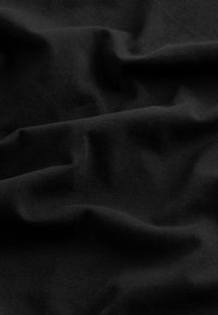 Tissu noir avec une texture douce et lisse, présentant une légère élasticité et un subtil éclat, visible dans des plis et des froissements.