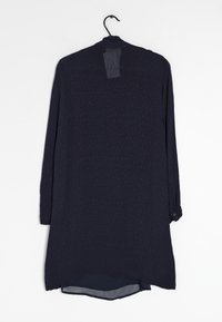 Camicia lunga blu navy su una gruccia, con un motivo floreale testurizzato, polsini con bottoni e un orlo posteriore più lungo.