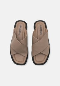 Tan leather slide sandals featuring a cross strap design, padded insole, and black rubber outsole. Brand name "SAMSØE" embossed.