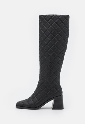 Bottes noires montantes avec un design texturé matelassé, bout carré et talon bloc. Fabriquées en matériau synthétique avec une finition lisse.