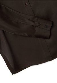 Camisa de manga larga marrón oscura, con textura suave, que presenta un cuello con puntas y puños de dos botones, con un dobladillo relajado y ligeramente curvado.