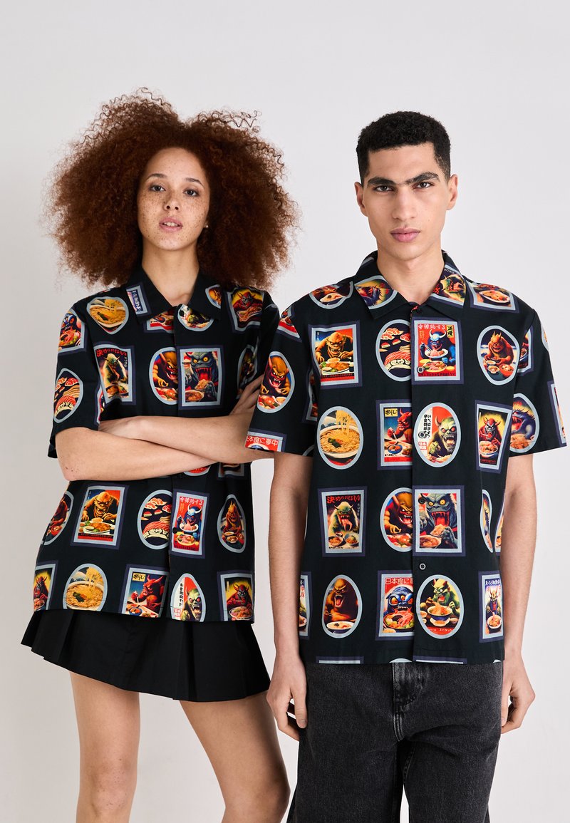 Korte mouwen shirts van zwarte stof met levendige retro-stijl voedsel- en monsterillustraties in gekleurde kader. Katoenmix, relaxte pasvorm.