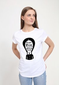 Bílá tričko s velkým černým grafickým vzorem, který obsahuje text a design postavy, slim fit, krátké rukávy a hladkou texturu látky.