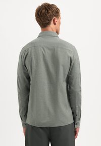 Grijze langemouwen shirt van textiel, met een spitse kraag, knoopmanchetten en een rechte zoom. Achteraan zien we geen patronen.