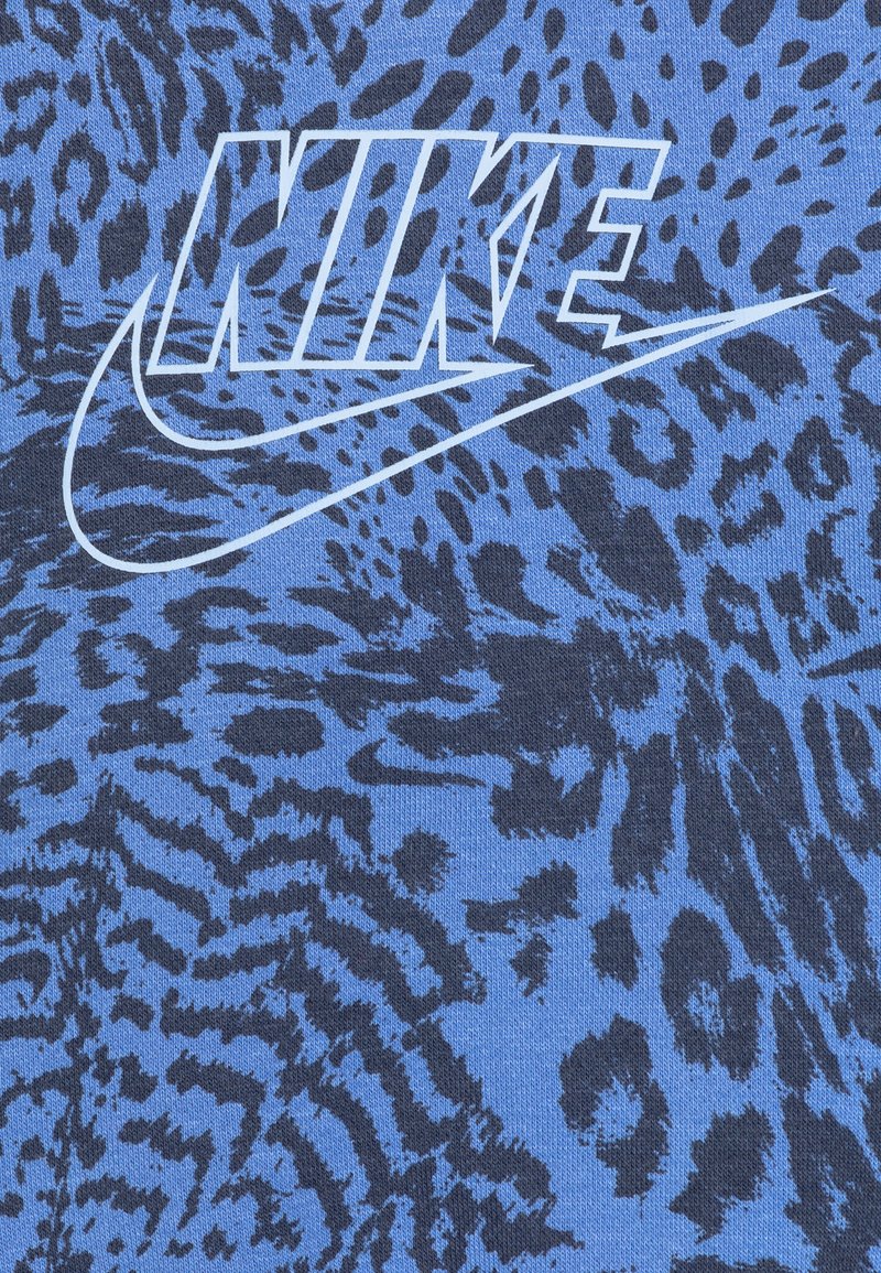 Tissu bleu avec un motif léopard en marine foncé. Logo Nike blanc affiché de manière proéminente, avec le design classique du swoosh.