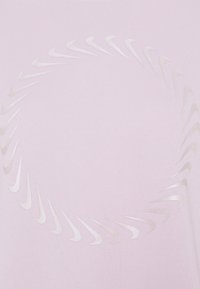 Circular pattern of small, white Nike swoosh logos on light pink fabric, creating a spiral design.