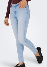 Ανοιχτό μπλε στενά τζιν από denim, με εφαρμοστή σχεδίαση, πέντε τσέπες και κλασική μέση με κουμπί μπροστά.