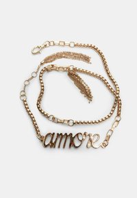 Collier en métal doré avec un design de maillons et un charme en texte "amore". Comprend des accents de chaînes superposées de longueurs et de textures variées.