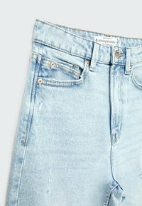 Ljusblå denim mom-slim fit-jeans med knappstängning, slitna detaljer och klassisk femficksdesign.