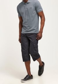 Grå pikétröja med korta ärmar, svarta cargoshorts med sidofickor och svarta sneakers. Avslappnad outfit med en lätt passform.