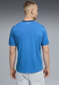 Μπλε αθλητική μπλούζα με κοντό μανίκι, λεία υφή, αντίθετο γιακά και διακριτικό λογότυπο της μάρκας στο πίσω μέρος. Ελαφρύ ύφασμα.