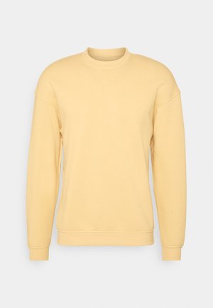 Sweatshirt jaune à encolure ronde, manches longues et poignets côtelés. Fabriqué en tissu doux avec une texture lisse. Design classique et décontracté.