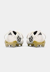 White soccer cleats featuring black stripes, a textured upper, and clear studs with a yellow sole. Includes laces and branding on the heel.