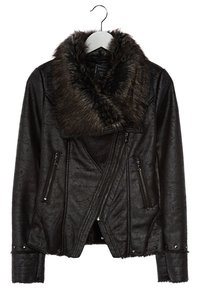 Veste en similicuir noir avec col en fausse fourrure, fermeture éclair asymétrique, poches zippées, finition texturée et ornements cloutés.