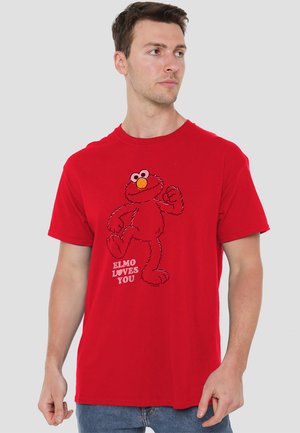 Rotes Baumwoll-T-Shirt mit einem schwarzen und roten Elmo-Graphic und dem Text "ELMO ♥ LIEBT DICH" in Weiß. Klassischer Rundhalsausschnitt und kurze Ärmel.