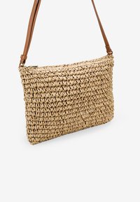 Borsa in paglia intrecciata di forma rettangolare, con una finitura naturale testurizzata e una tracolla in pelle marrone. Chiusura con zip lungo la parte superiore.