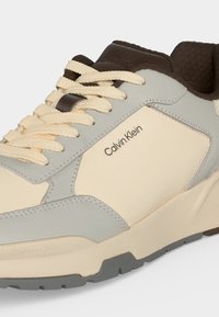 Αθλητικό παπούτσι Calvin Klein σε μπεζ, γκρι και καφέ με κορδόνια κρεμ, ορατό λογότυπο της μάρκας στο πλάι και στη γλώσσα, υφασμένο πέλμα και επενδυμένος αστράγαλος.