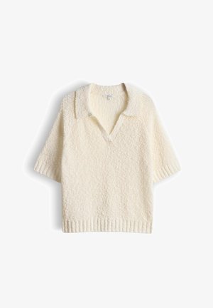 Pull en maille texturée de couleur crème à manches courtes avec col et ouverture en V, présenté sur un fond blanc.