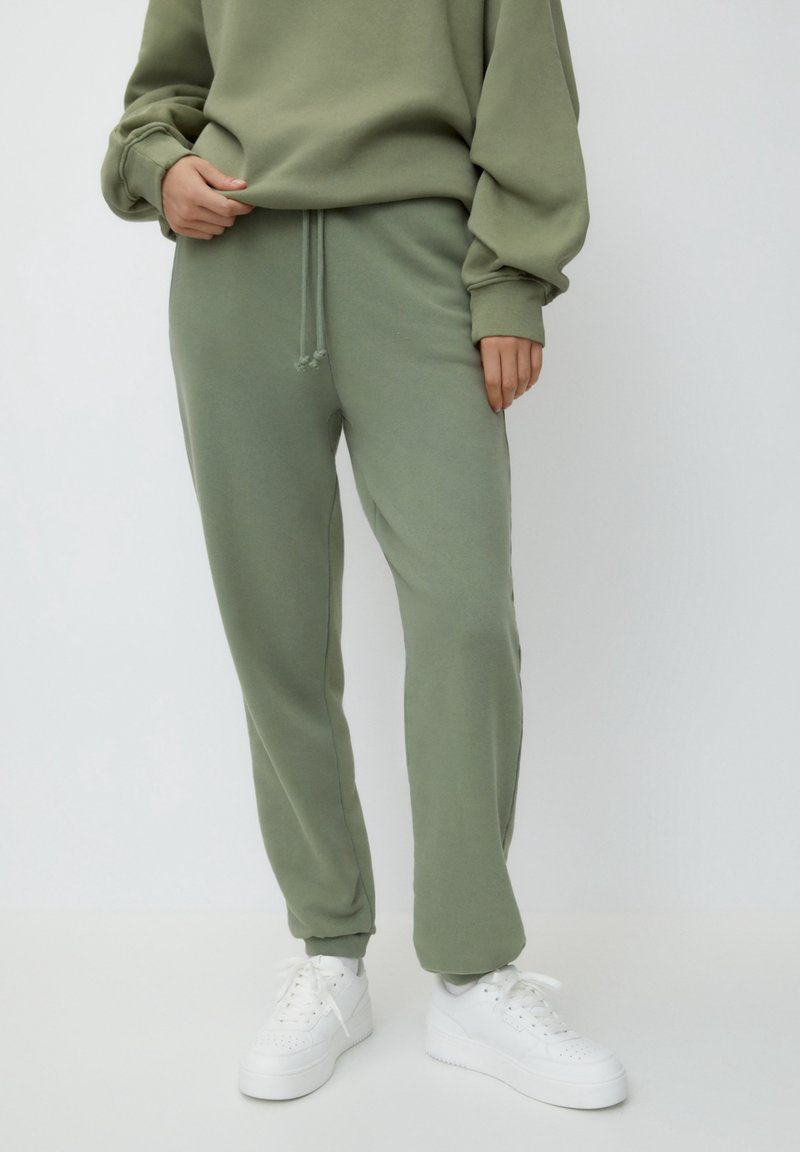 Lichtgroene joggingbroek met een elastische tailleband en trekkoord. Gecombineerd met witte sneakers, gemaakt van een gladde, licht gestructureerde stof.