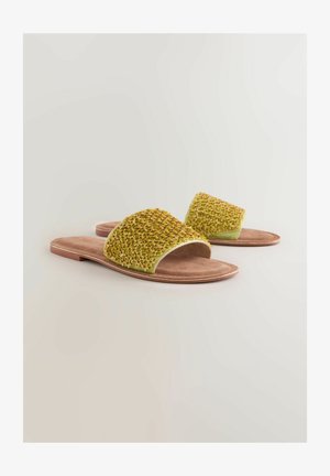 Grüne Schlappen mit einem strukturierten Obermaterial, das ein geflochtenes Muster aufweist. Weiche beigefarbene Innensohle und hellbraune Außensohle. Offenes Zehendesign.