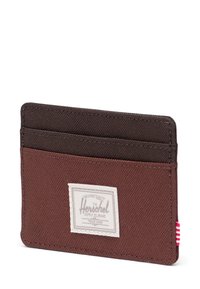 Brązowy portfel na karty z ciemnobrązowym akcentem. Ma cztery sloty na karty, białą łatę z logo oraz paskowany akcent na krawędzi.
