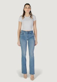 Jeans azzurri chiari a vita alta con gamba dritta, design a cinque tasche e una leggera scoloritura. Indossati con una maglietta aderente bianca a coste.