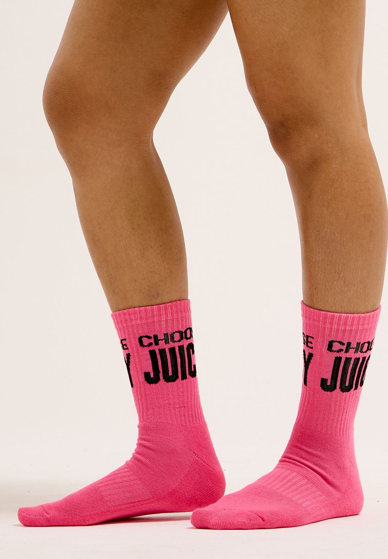 Calze rosa a coste con una stampa nera che recita "CHOOSE JUICY" attorno alla parte superiore. Texture morbida con un design alla caviglia.