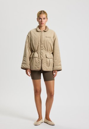 Beige gesteppte Jacke mit Kragen, taillierte Taille und zwei Fronttaschen. Glatte Textur mit braunen Akzenten entlang der Kanten.