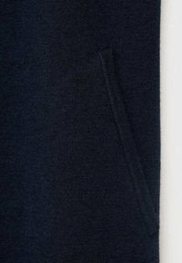Donker marineblauw gebreide stof met een verticale sleufzak, voorzien van ribbels aan één rand.