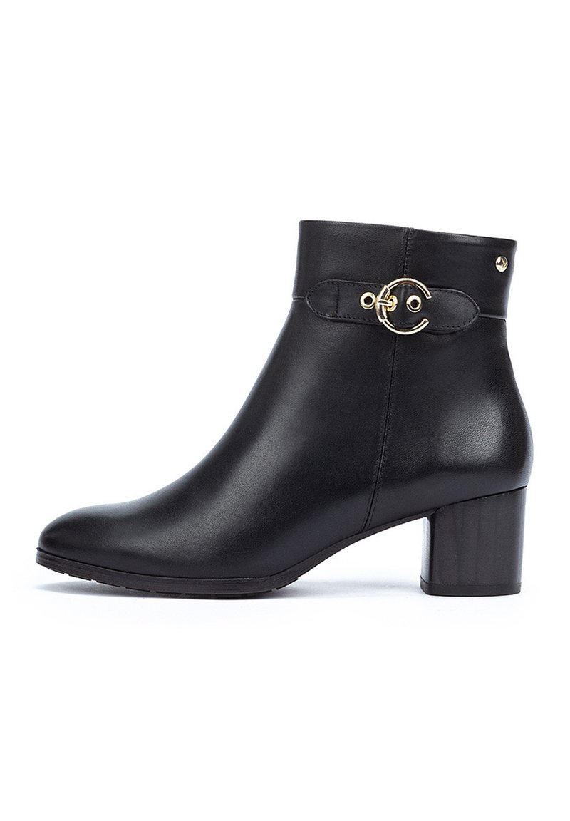 Botte de cheville en cuir noir avec un bout rond, un talon épais et un accent circulaire doré sur le côté. Texture lisse avec un minimum de détails.
