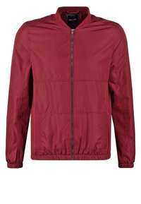 Giacca bomber bordeaux, tessuto liscio, chiusura con zip frontale, due tasche laterali, polsini e vita elasticizzati, presenta dettagli di cucitura minimali.