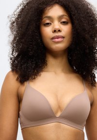 Vaaleanruskea, saumaton kolmio rintaliivi ohut säädettävä hihnoilla ja sileällä, joustavalla kankaalla. Minimalistinen muotoilu, ei näkyviä kiinnikkeitä.