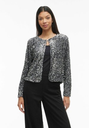 Silver sequined jacket with a round neckline, front hook closure, and long sleeves, paired with a black top and wide-leg pants.
