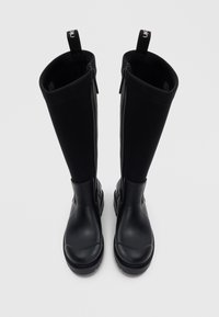 Bottes noires jusqu'au genou avec une finition en caoutchouc lisse, dotées d'une fermeture éclair à l'avant, avec une tige en textile et une semelle robuste. Tirant en haut.