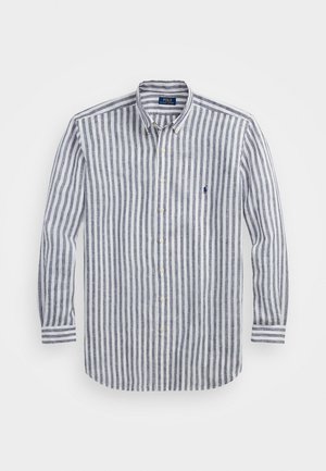 Camisa de botones a rayas en lino azul y blanco, con cuello en punta, mangas largas y un pequeño logo en el pecho.