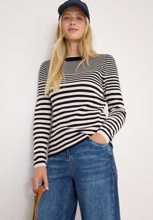 Pull en tricot rayé bleu marine et crème, avec des manches longues et un col rond, associé à un jean large bleu clair.
