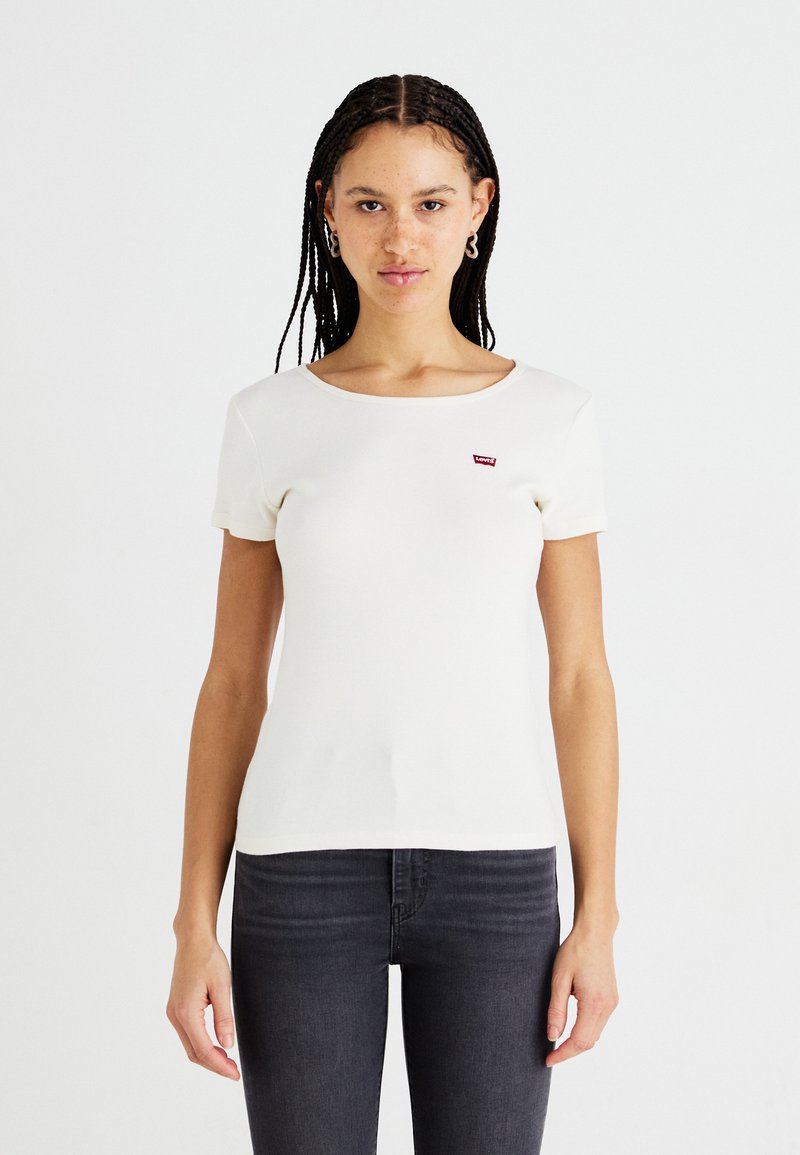 T-shirt blanc à manches courtes avec un col rond et un petit logo rouge Levi's sur la poitrine. Fabriqué à partir d'un matériau lisse et extensible.