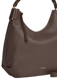 Borsa a spalla in pelle marrone con superficie texturizzata, forma curvata, hardware dorato e chiusura con zip. Nome del marchio visibile sulla parte anteriore.