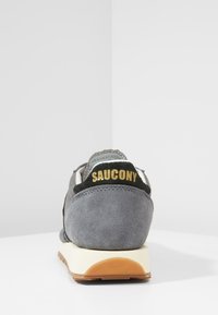 Šedé semišové tenisky Saucony pohledem z profilu na bílé ploše s světle šedým a bílým pozadím.