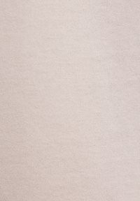 Tissu beige tricoté avec une couture fine et régulière, une texture douce et lisse, dans une couleur neutre beige clair.