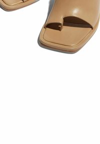 Beige open-toe sandalen met een vierkante vorm, gemaakt van soepel leer, met een enkele band en teenlus. Platte hak, minimale accenten.