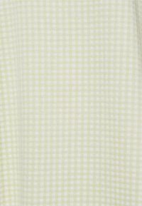 Tecido em padrão xadrez verde-claro e branco com uma textura suave e design de grelha quadrada. O material parece leve e tecido.