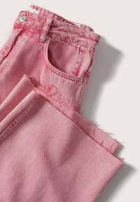 Jean en denim rose plié, montrant un bouton en métal et des détails de la poche avant, avec des ourlets effilochés aux jambes.