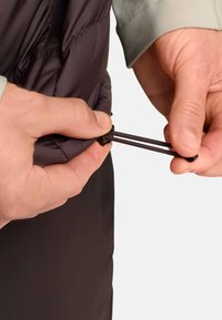 Zwarte geïsoleerde vest met een gladde textuur, voorzien van een verstelbare trekkoordsluiting. Handen grijpen het trekkoord om het aan te trekken.