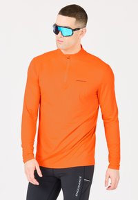 Klarr orange långärmad skjorta med halvmått krage, stretchigt tyg och diskret varumärkeslogotyp. Bärs med svarta figursydda byxor.
